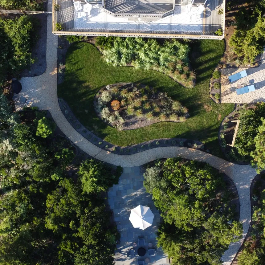 An overhead view of Surf House's deck, curved garden beds, lawn, gravel paths, and secluded seating areas.