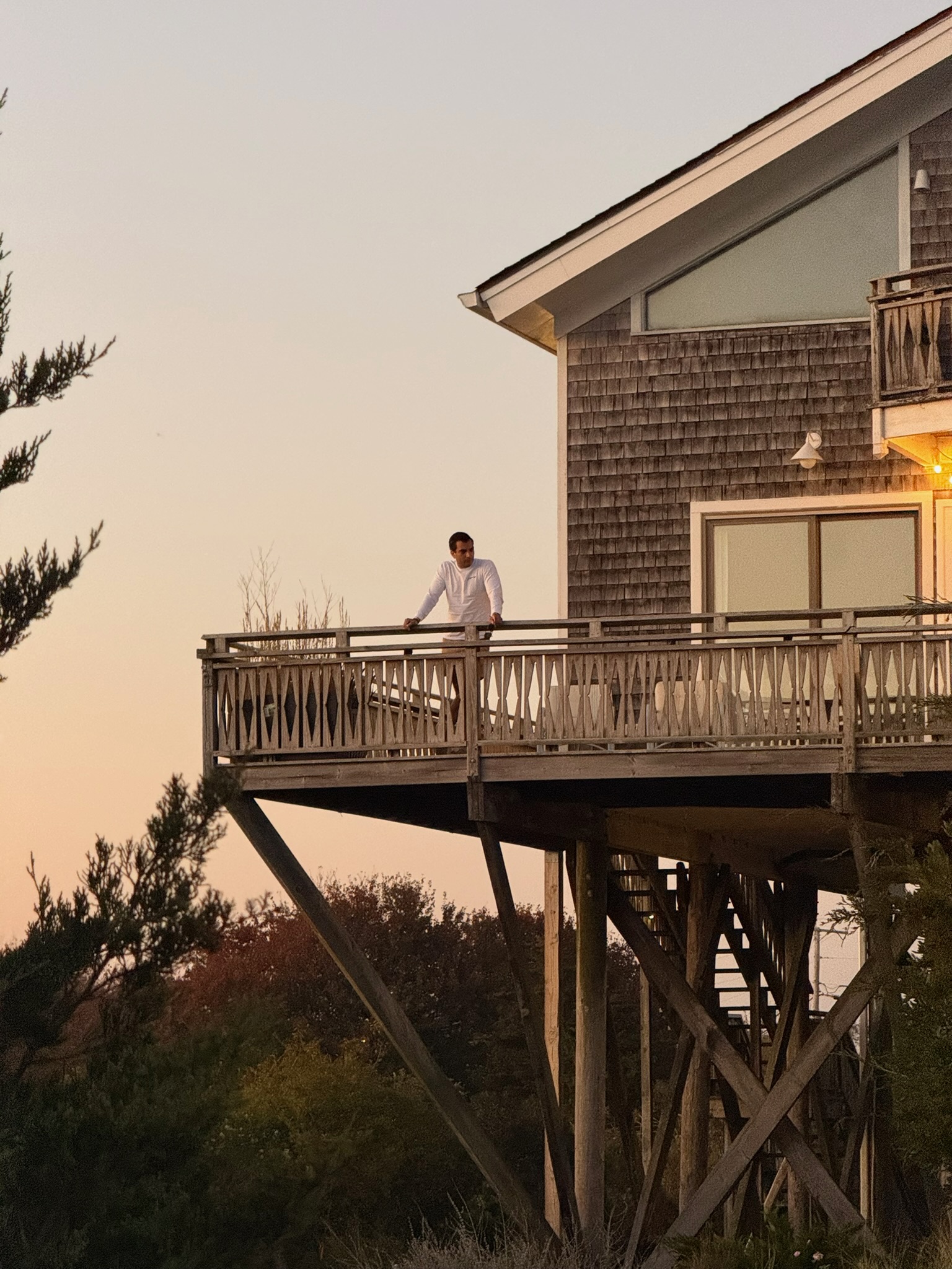 A person enjoying the Surf House balcony in warm evening light.
