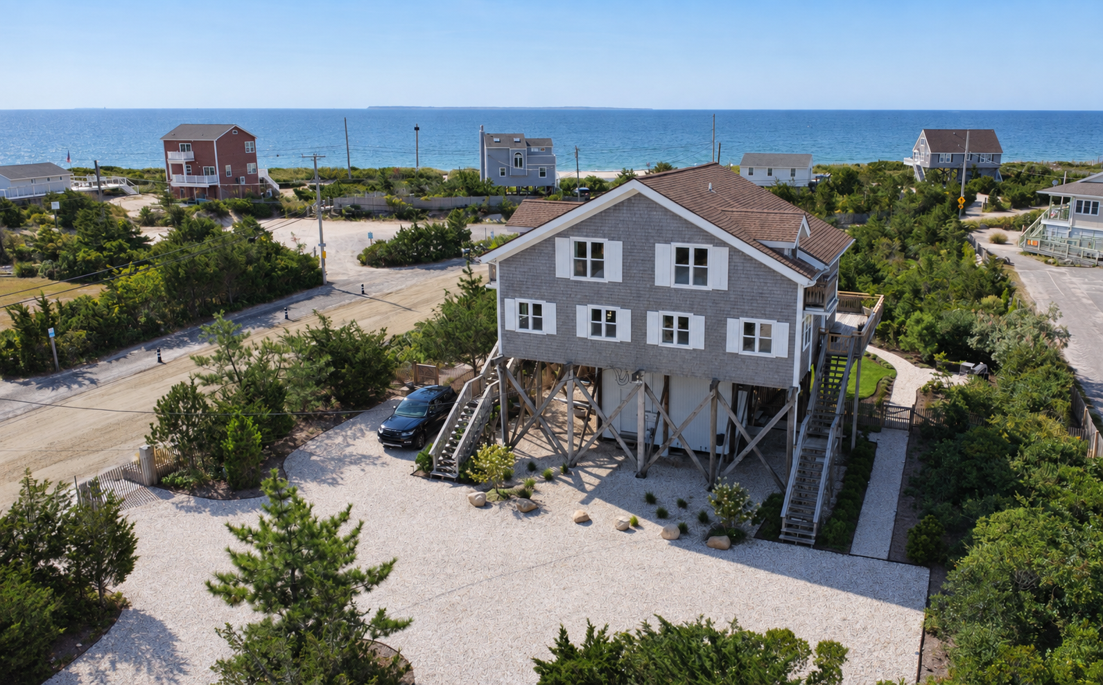 An aerial view of Surf House with the beach and ocean beyond.